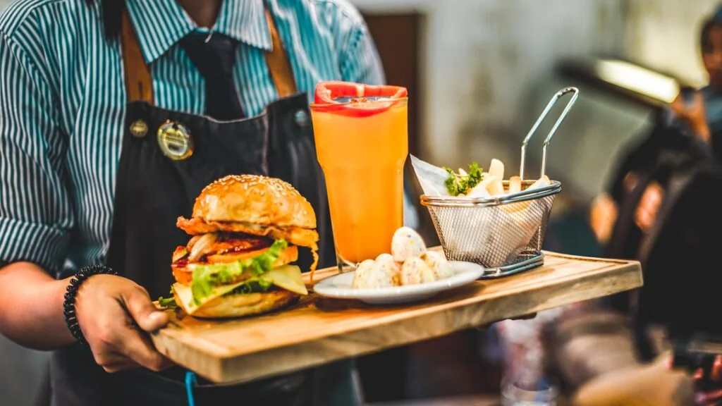 Coco Bambu person serving burger with pitcher of juice