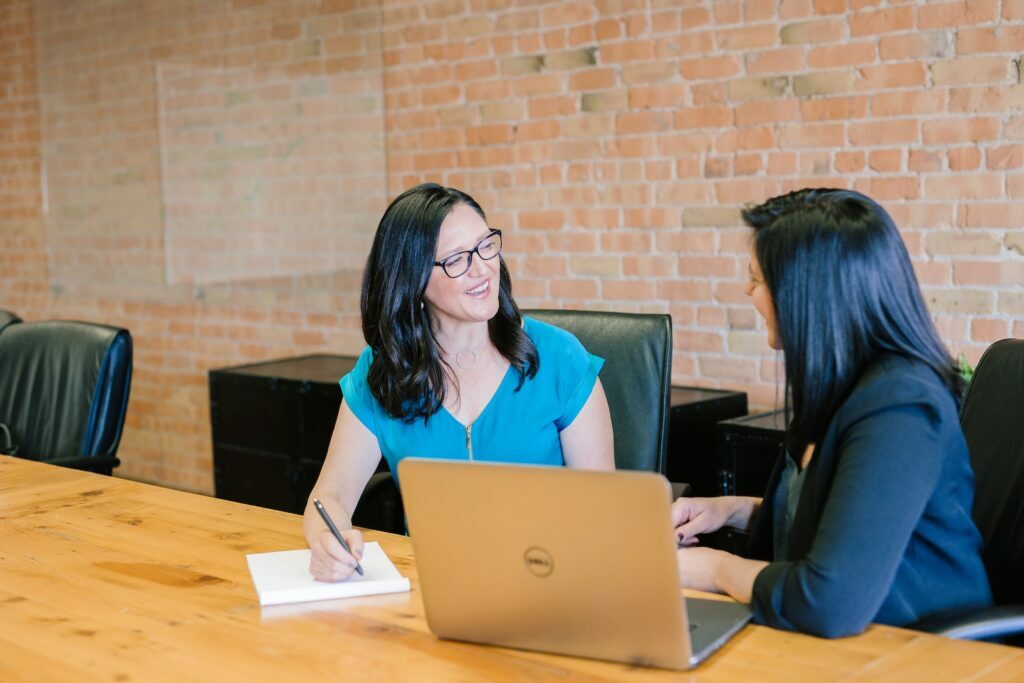 Personale Consultoria woman in teal t-shirt sitting beside woman in suit jacket
