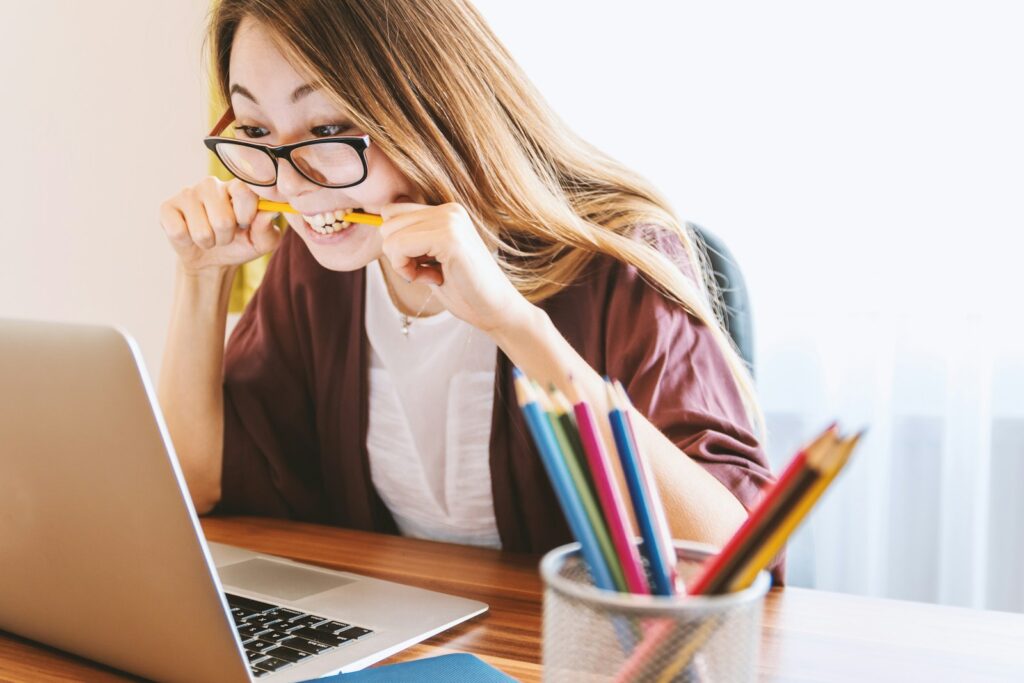 Saúde mental agora é lei nas empresas: Atualização da NR-1 woman biting pencil while sitting on chair in front of computer during daytime