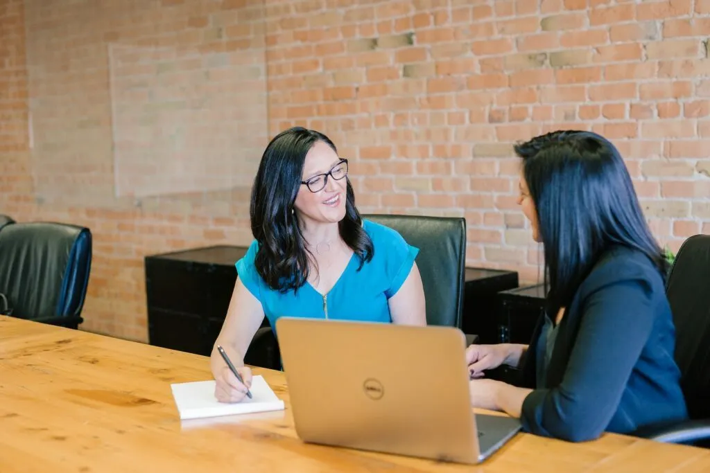 Personale Consultoria woman in teal t-shirt sitting beside woman in suit jacket