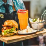 Coco Bambu person serving burger with pitcher of juice
