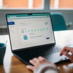 Auxiliar Administrativo e Assistente Acadêmico, Vagas 100% Home Office Person using a laptop to review a rewards program.